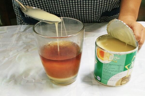 Sau khi đã pha trà với nước nóng thì cho tiếp sữa đặc vào khuấy đều cho tan.