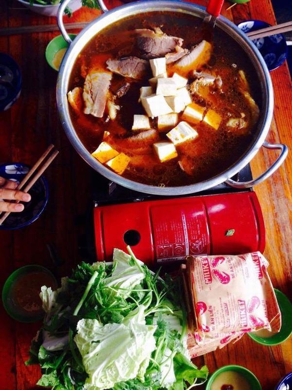 A big pot of hot pot with accompanying vegetables, shrimp noodles, tofu and big pieces of beef